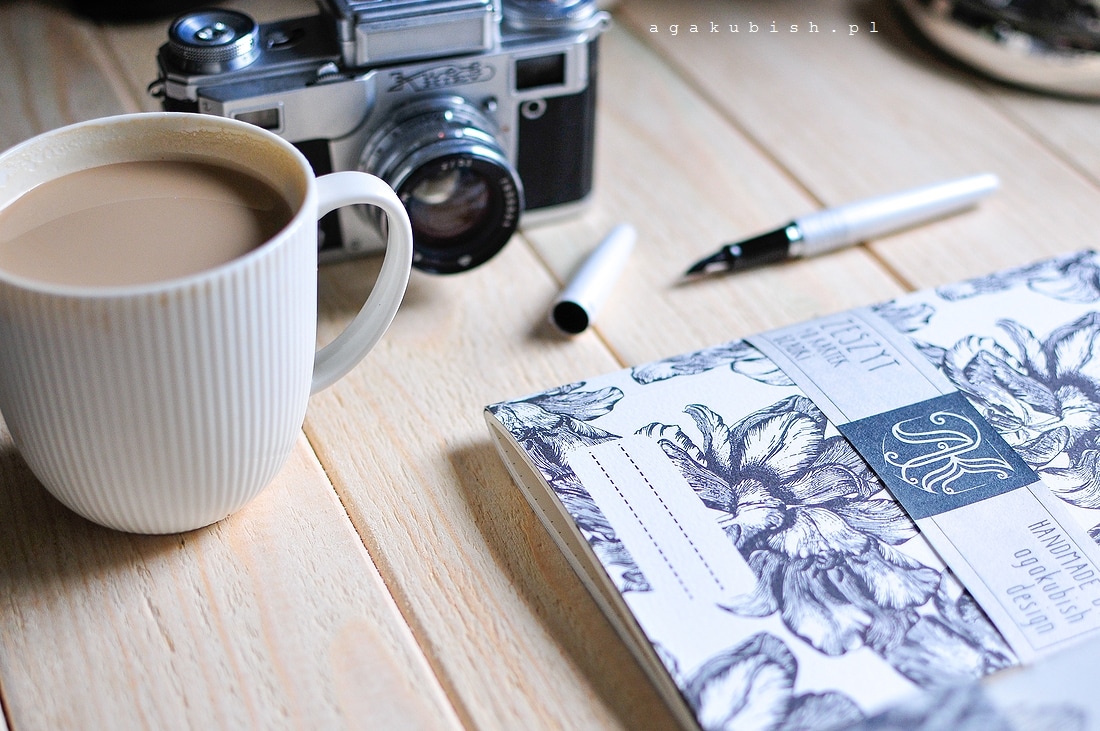 Zeszyt ręcznie robiony z tulipanami i kawą oraz starym aparatem na biurku agakubish design